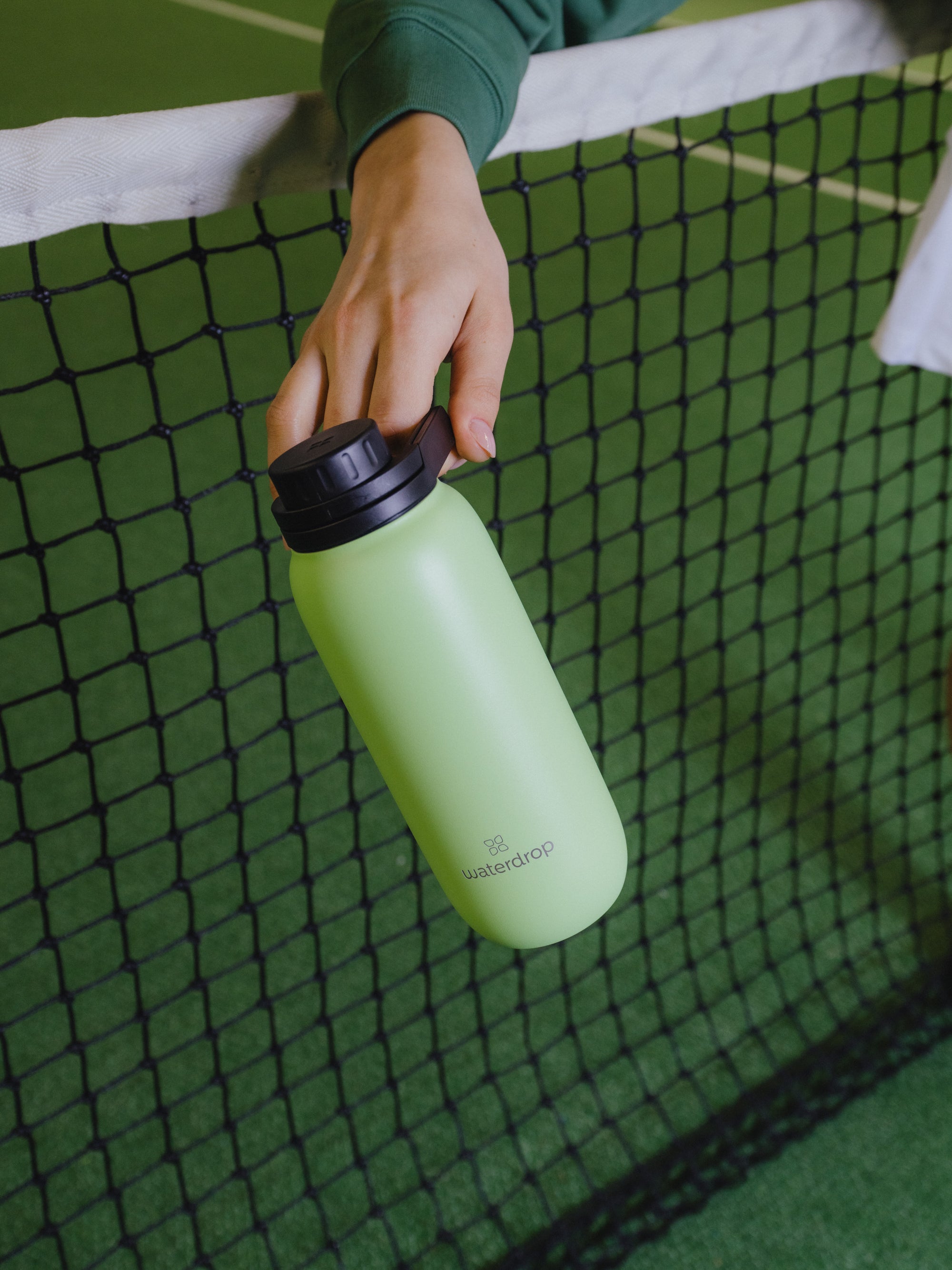 waterdrop® All-Purpose Bottle with Flip Lid carried in one hand on a tennis court