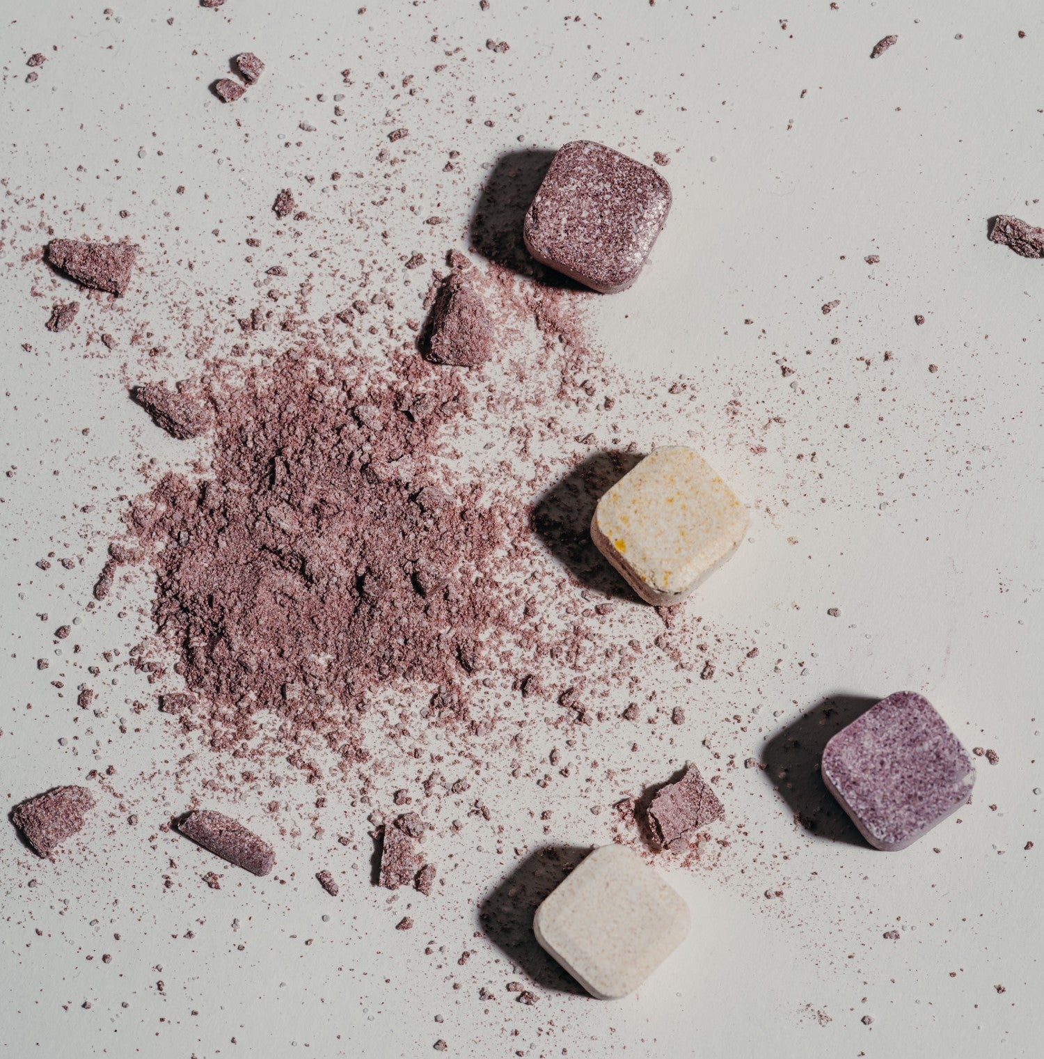 Several waterdrop hydration cubes on a flat surface, with some crushed into powder, creating a scattered effect.