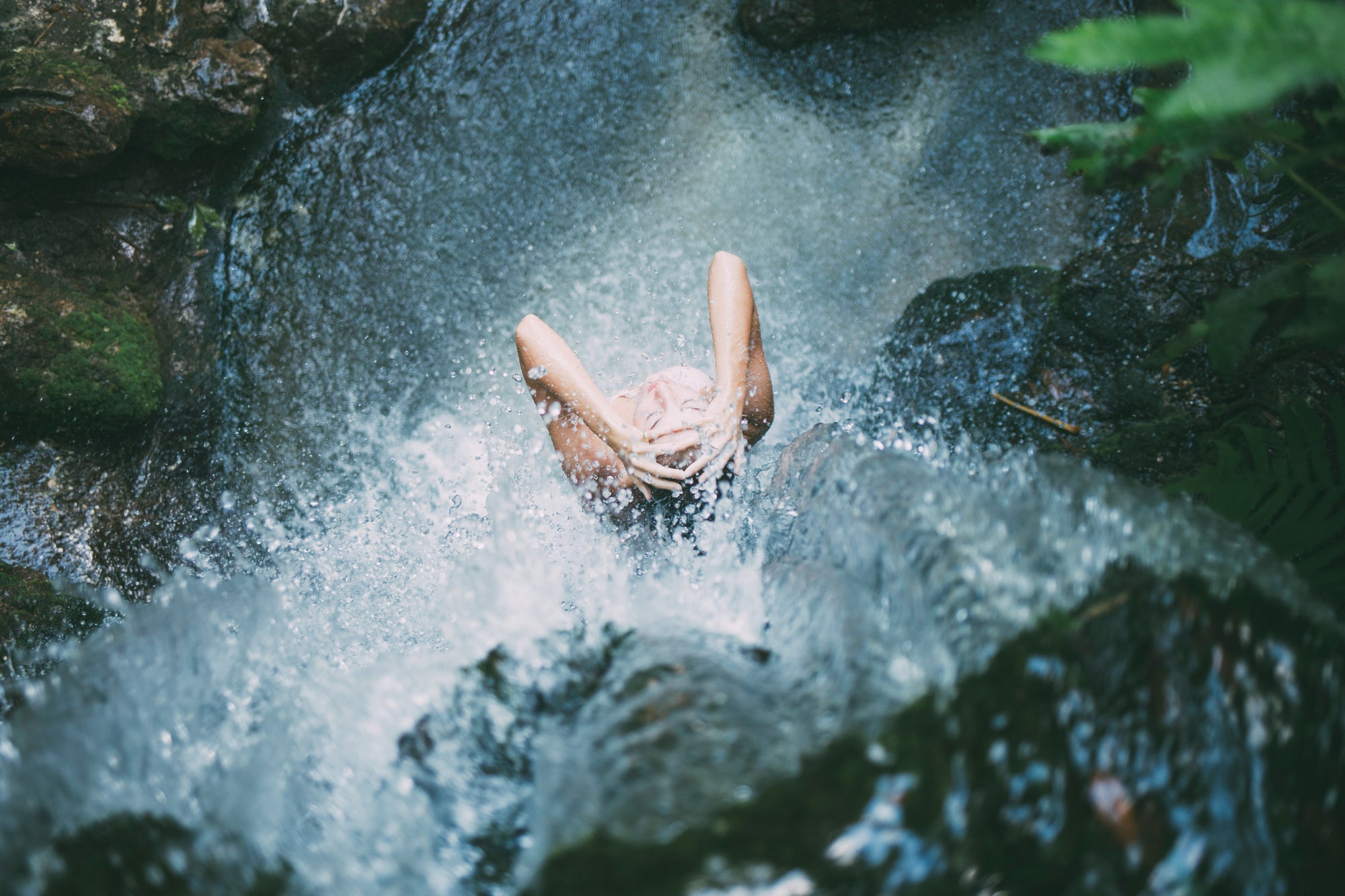 A person from above, taking a shower under a waterfall