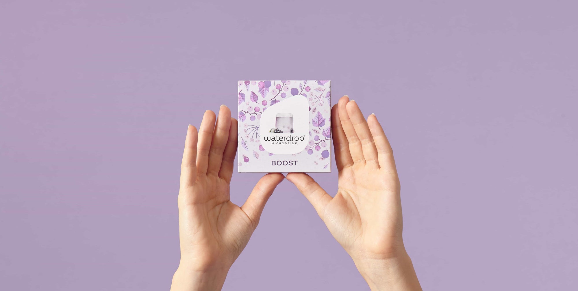 Hands holding Waterdrop BOOST microdrink 12-pack with purple floral design on lavender background.