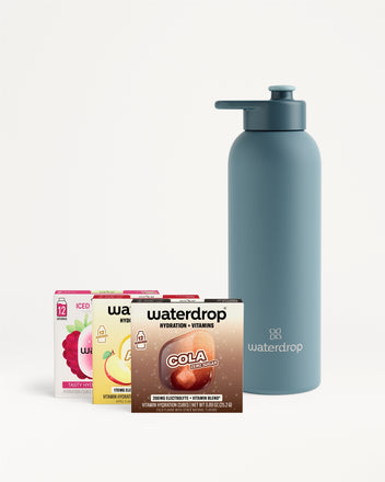 Blue reusable water bottle with a pump-top spout beside a set of flavor packet boxes.