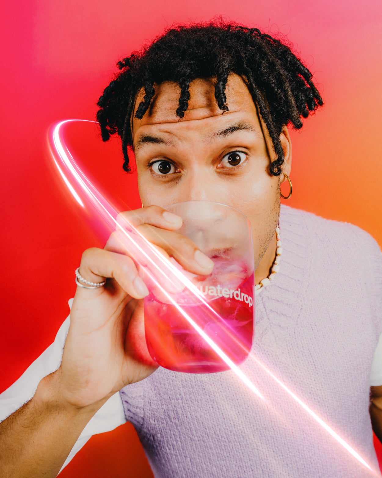 Young person sipping BERRY BOOST from a translucent waterdrop cup.