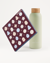 Purple square box with circular icons leaning against a light green bottle with a wooden cap.