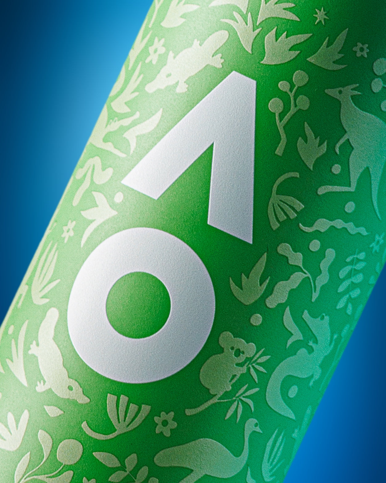 Close-up of a green cylindrical bottle with a large white geometric emblem and decorative white silhouettes against a blue background.